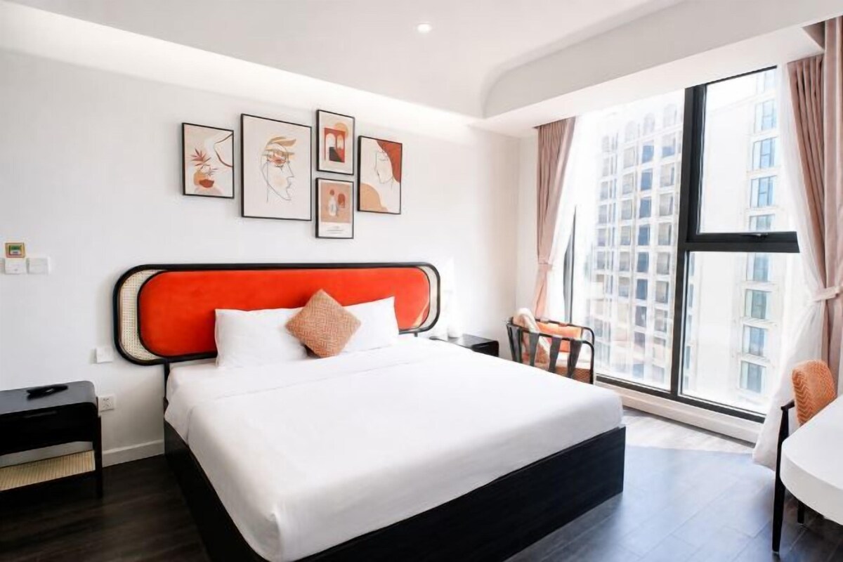 A hotel room with a large bed, a desk, and a window with curtains.