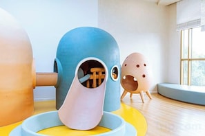 Zona infantil con un tobogán y dos estructuras de juego esféricas.