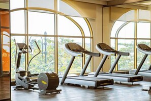 A gym with treadmills and elliptical machines, large windows, and wooden flooring. - Seaside Fireworks Apartment Free Pool & Gym (Phu Quoc Island)