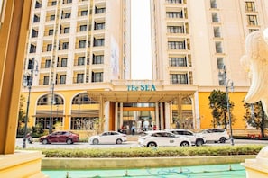 Un hotel con una entrada amplia, varios pisos y un área de piscina.