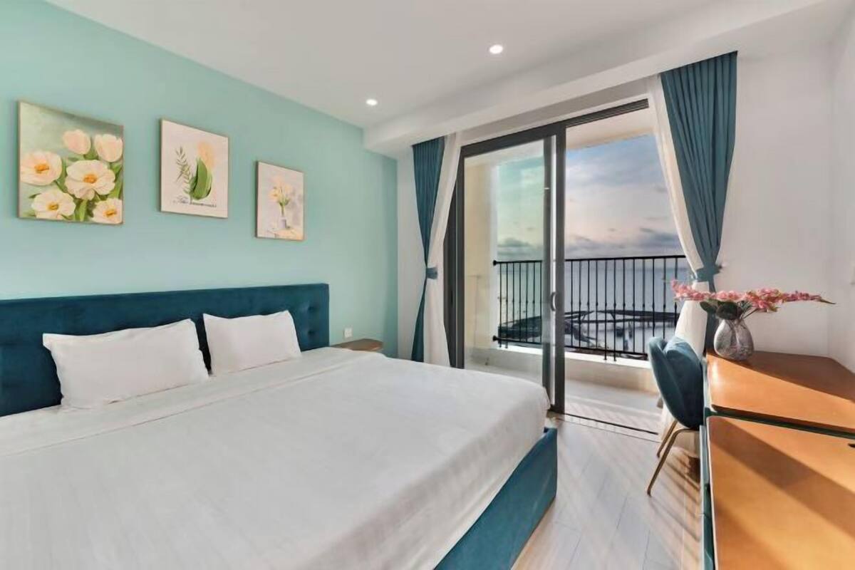 Una habitación de hotel con cama, escritorio y balcón con vistas.