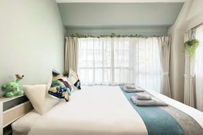 A bedroom with a bed, pillows, a bedside table, and a window with curtains.