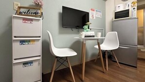 Une cuisine compacte équipée d’un téléviseur, d’un réfrigérateur et d’une petite table à manger avec des chaises.