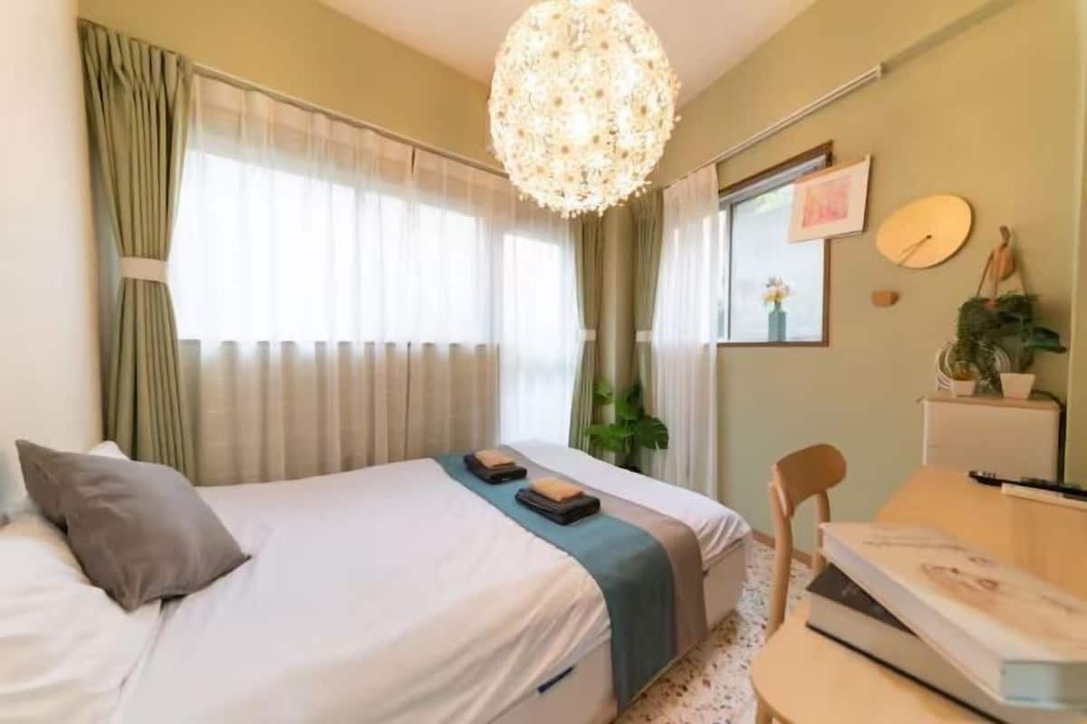 A neatly arranged bedroom with a bed, bedside table, and a desk.