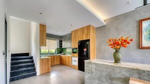 Een moderne keuken met houten kastjes, een zwarte koelkast en een bloemenvaas op het aanrecht.