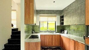 Een moderne keuken met houten kastjes, een granieten aanrechtblad en een raam met jaloezieën.