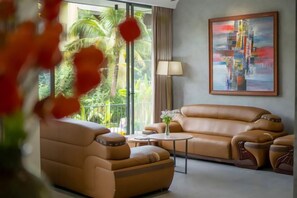Un salon moderne avec un canapé, des fauteuils, une table basse et un tableau au mur.
