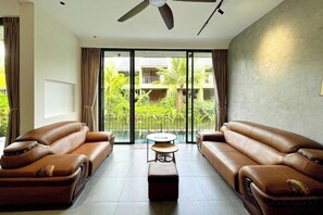 A modern living room with leather sofas, a round coffee table, and a ceiling fan.