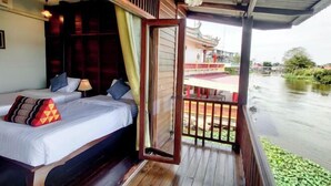 Een kamer met twee bedden, een houten plafond en uitzicht op een rivier.