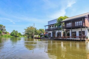 Un edificio de dos pisos con un balcón, ubicado junto a una masa de agua tranquila.