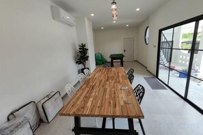 Een vergaderzaal met een lange houten tafel, zwarte stoelen, een groene bank en een tafeltennistafel.
