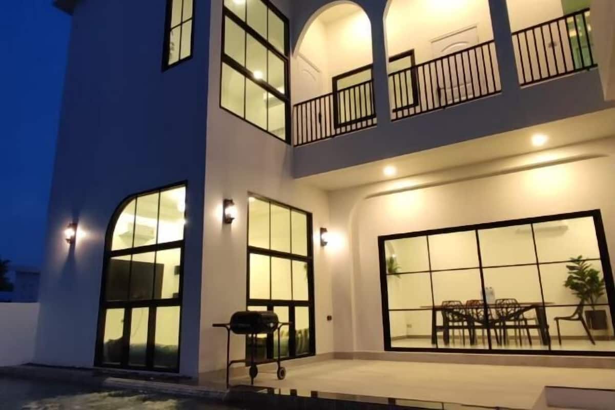 A multi-story building with large windows, a balcony, and a dining area.