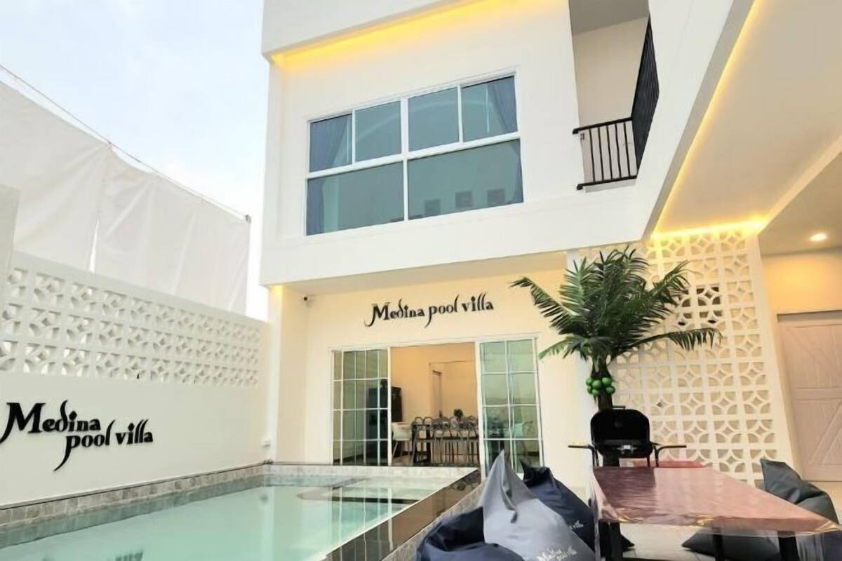 A villa with a glass-bottomed pool, a dining area with a table and chairs, and a sign reading 'Medina pool villa.'