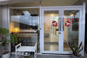 En moderne entré med en glasdør, et lille siddeområde og en potteplante.