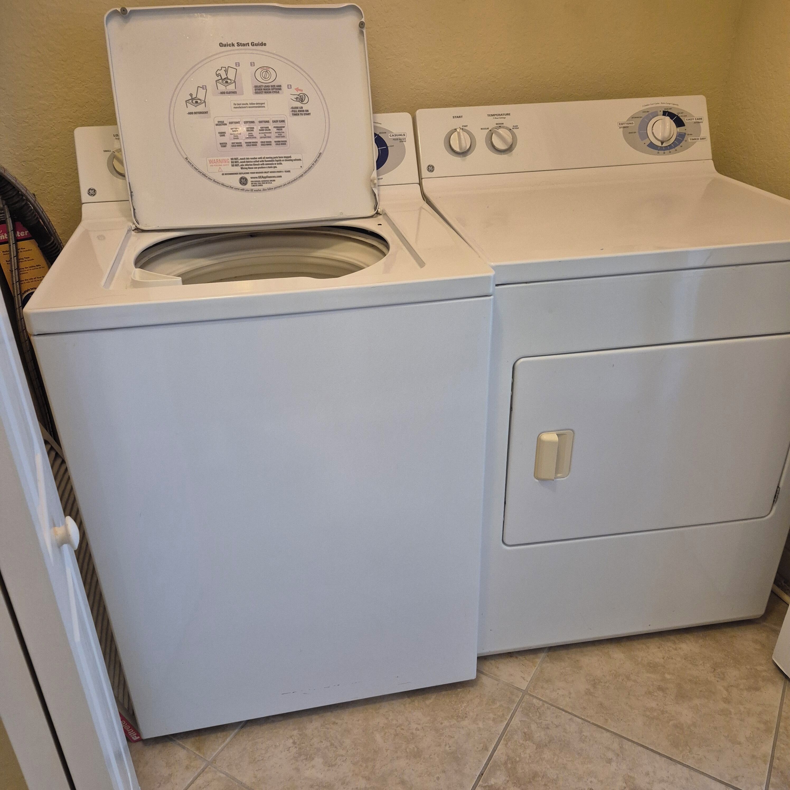 A front-loading white washer and dryer unit with a Quick Start Guide on top, control knobs, and a front door.