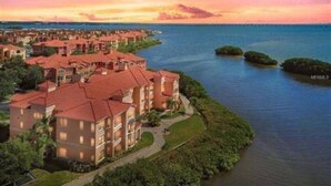 Un hotel costero con varias edificaciones, un paseo marítimo y vistas al atardecer.