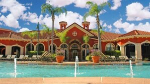 Un hotel con piscina, palmeras y fachada roja.