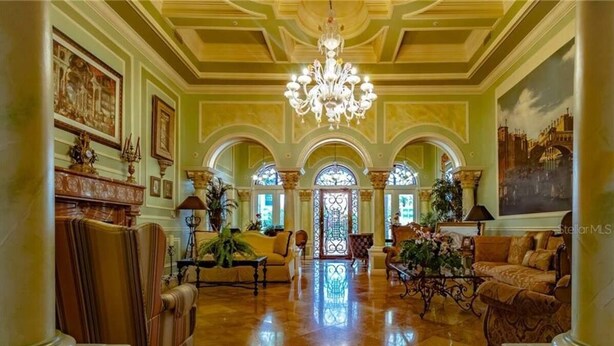 Un amplio vestíbulo con candelabro, ventanas de arco y muebles clásicos.