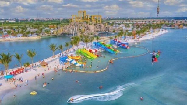 A water park with a large body of water, multiple water slides, and a sandy beach area. - Emiii House - Homestay Near The Wave Park Vinhomes Ocean Park 2 (Nghia Tru)
