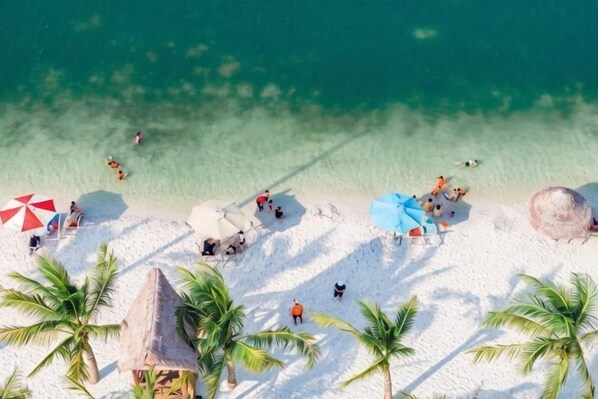 Una playa con agua turquesa cristalina, arena blanca y palmeras.