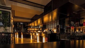 A modern bar area with a long counter, ambient lighting, and a variety of bottles and glasses. - Emiii House - Homestay Near The Wave Park Vinhomes Ocean Park 2 (Nghia Tru)