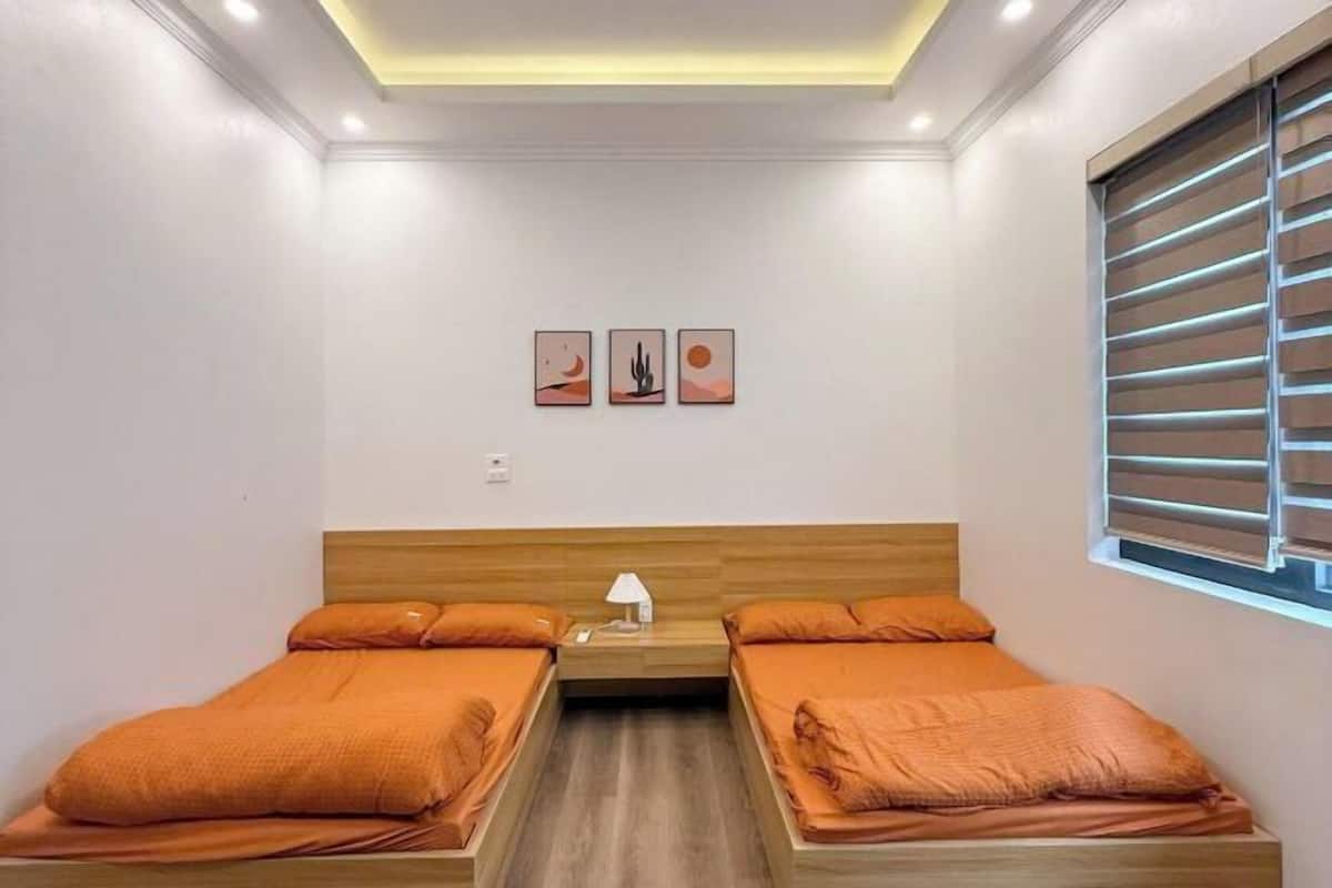 Une chambre avec deux lits, une table de chevet, une lampe et trois tableaux accrochés au mur.