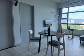 Une pièce comprenant une table à manger, des chaises, un t éléviseur et une grande fenêtre donnant sur un beau paysage.