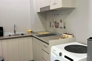 Une cuisine de taille réduite, équipée d’un évier, d’une cuisinière et d’un petit plan de travail.
