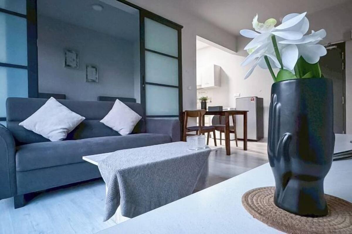 A modern living room with a grey sofa, a coffee table, and a vase with white flowers.