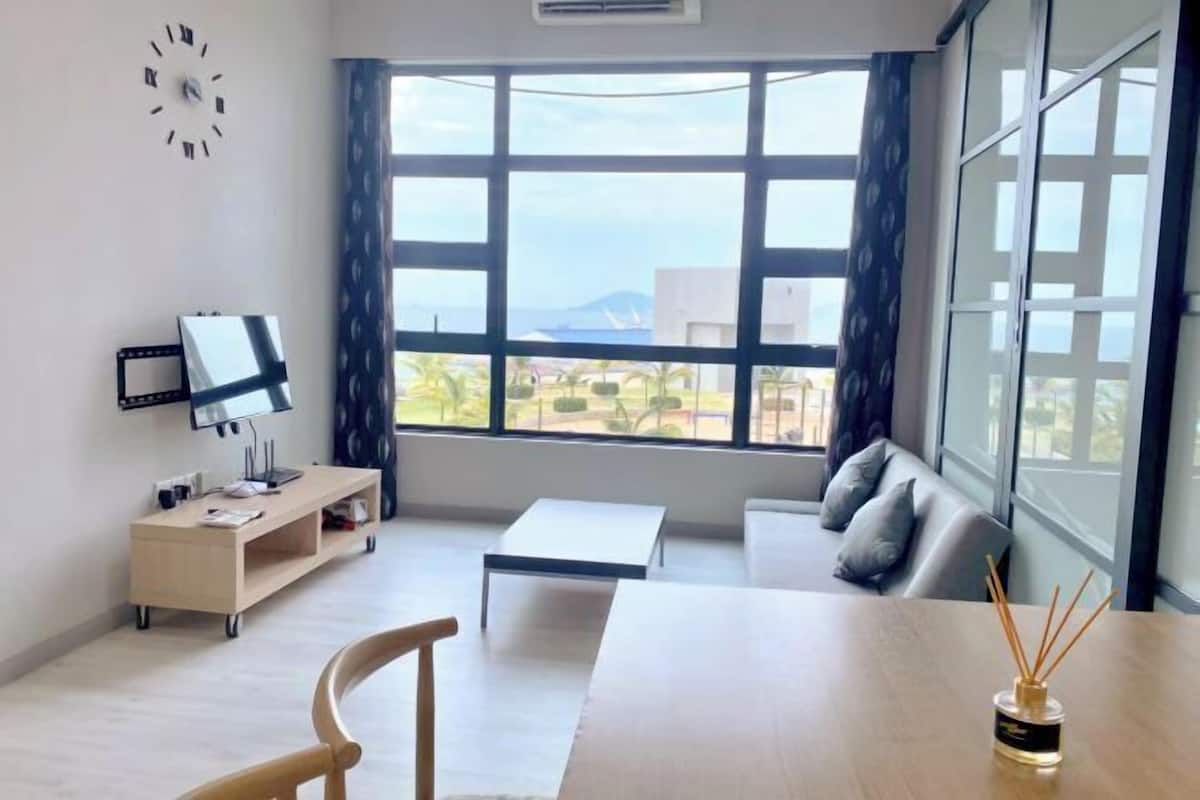 A modern room with a large window, a desk with a computer, a sofa, and a small table.