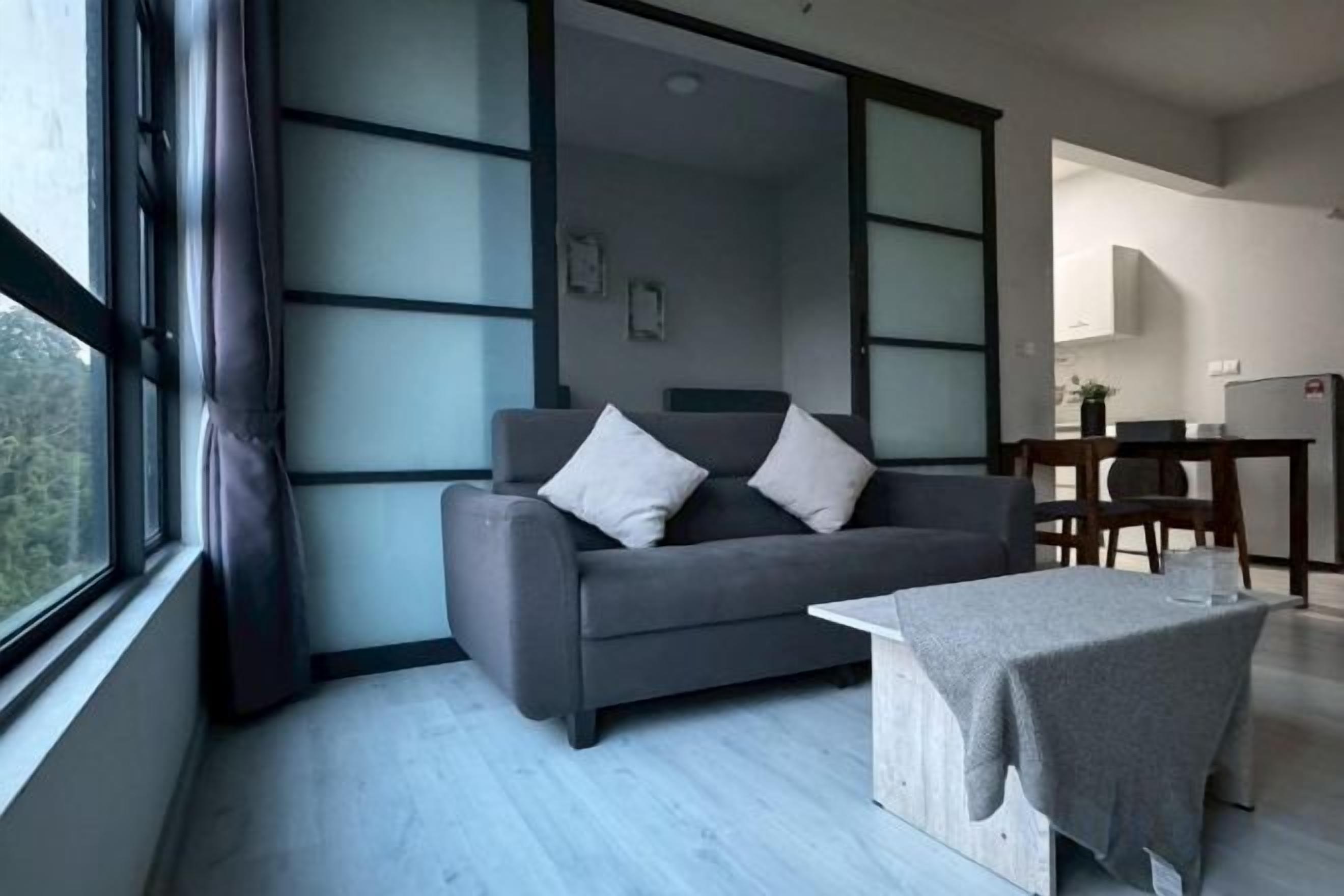 Ein stilvolles Wohnzimmer mit einer Couch, einem Couchtisch und Blick durch ein großes Fenster.