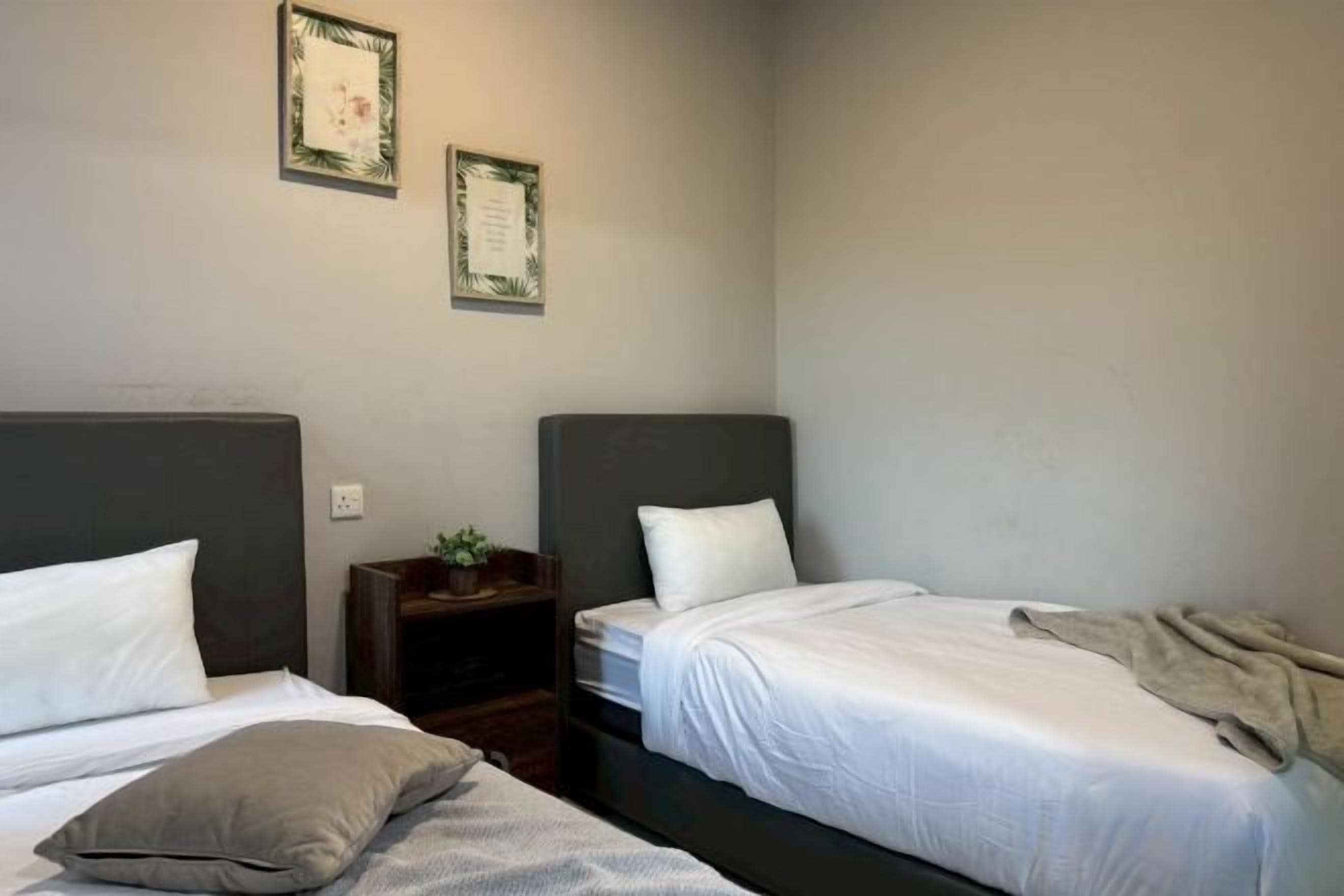A hotel room with two single beds, a nightstand, and a small table.