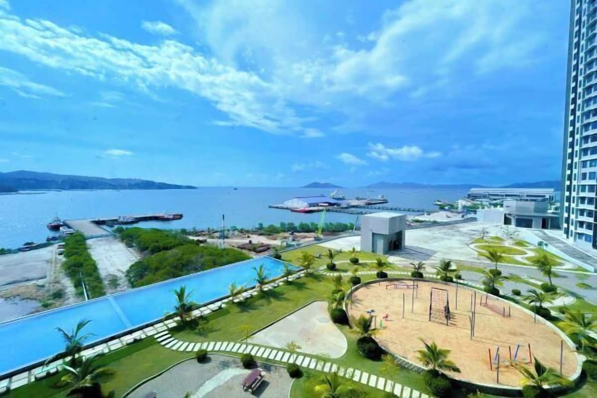 A resort with a swimming pool, a sandy area, and a view of the sea.