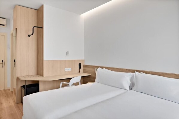 Una habitación de hotel moderna con cama, escritorio y armario.