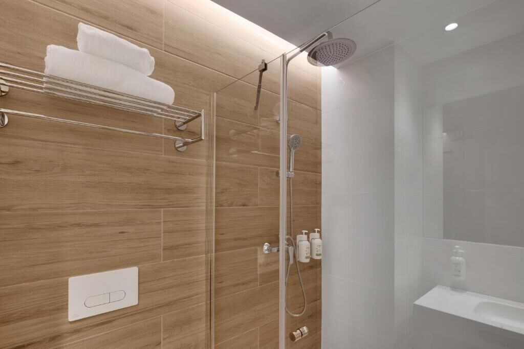 Un baño moderno con ducha de vidrio, un perchero para toallas y un lavamanos.