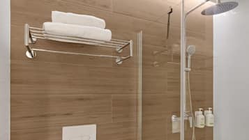 A shower with a handheld showerhead, a glass-enclosed shower stall, and a towel rack with two white towels.