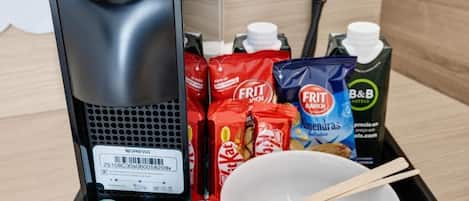 A coffee machine, snacks, a bowl with chopsticks, and a B&B juice carton.