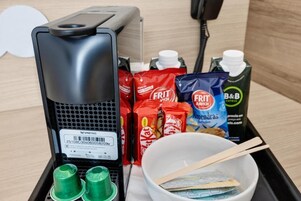 Una cafetera, aperitivos, un tazón con palillos y un cartón de jugo de B&B.
