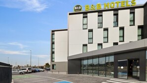 A B&B hotel with a modern facade, a parking lot, and a blue handicapped parking space.