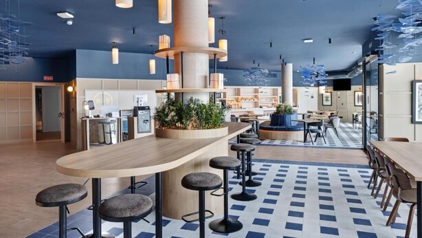 A modern bar area with a curved counter, bar stools, and pendant lighting.