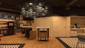 A modern hotel lobby with a reception desk, a coffee station, and a seating area.