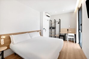 Et moderne hotelværelse med en stor seng, et skrivebord, en stol og et klædeskab.
