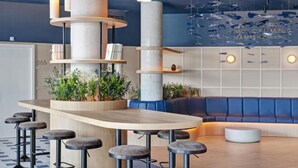 A modern bar area with a wooden counter, stools, and a blue seating area.