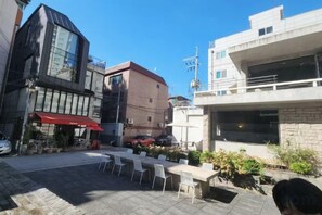 An outdoor seating area with tables and chairs, a red awning, and a building with a brick facade. - Near Hongik University/Subway Hapjeong Station 1 minute/8ppl/3br/4QBED/Near YG/iMac/Luggage storage (Seoul)