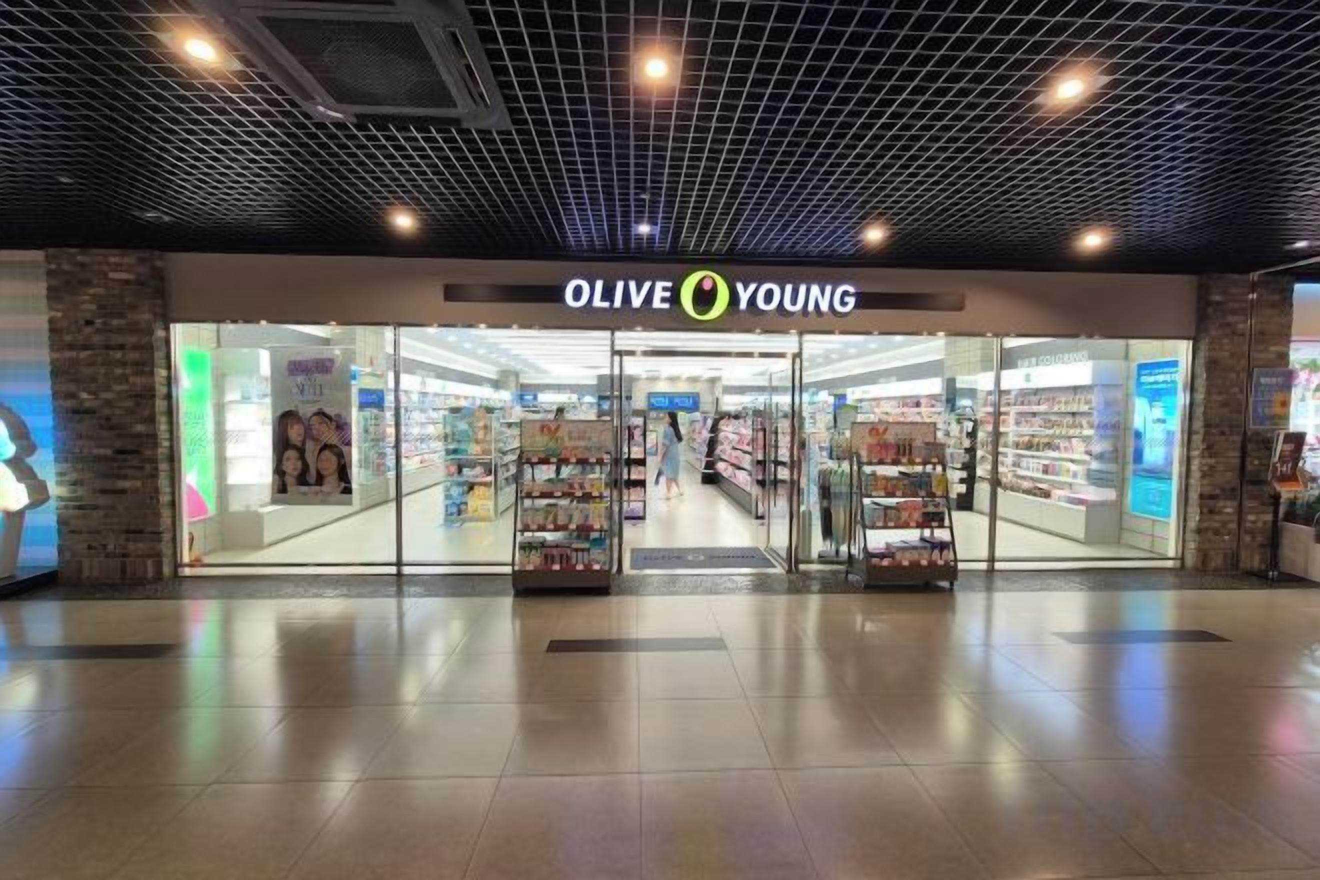 Una tienda llamada 'OLIVE YOUNG' con fachada de vidrio y suelo de baldosas.