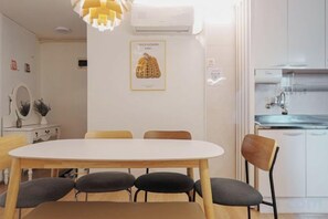 A dining area with a white table and chairs, a pendant light, and a kitchen with white cabinets and a sink. - Near Hongik University/Subway Hapjeong Station 1 minute/8ppl/3br/4QBED/Near YG/iMac/Luggage storage (Seoul)
