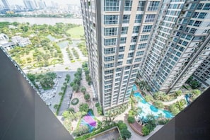 Un edificio de gran altura con múltiples balcones que dan a un área ajardinada con piscina.