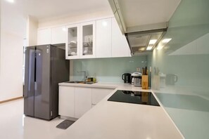 Una cucina moderna con frigorifero integrato, mobili bianchi e piano di lavoro nero.