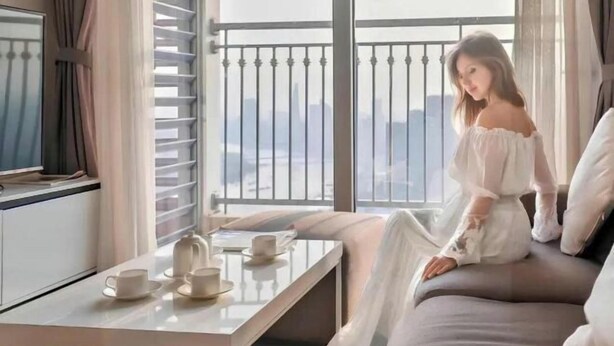 A room with a balcony, a sofa, a table with cups and a teapot, and a city view. - The Peninsula Apartment Landmark (Ho Chi Minh City)