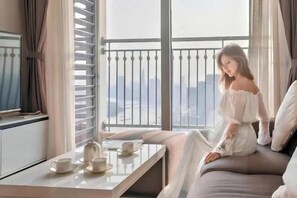 A room with a balcony, a sofa, a table with cups and a teapot, and a city view. - The Peninsula Apartment Landmark (Ho Chi Minh City)
